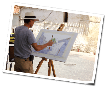 Professional artist Klaus Hinkel painting in the street of the white village Frigiliana in Andalusia a street scene
